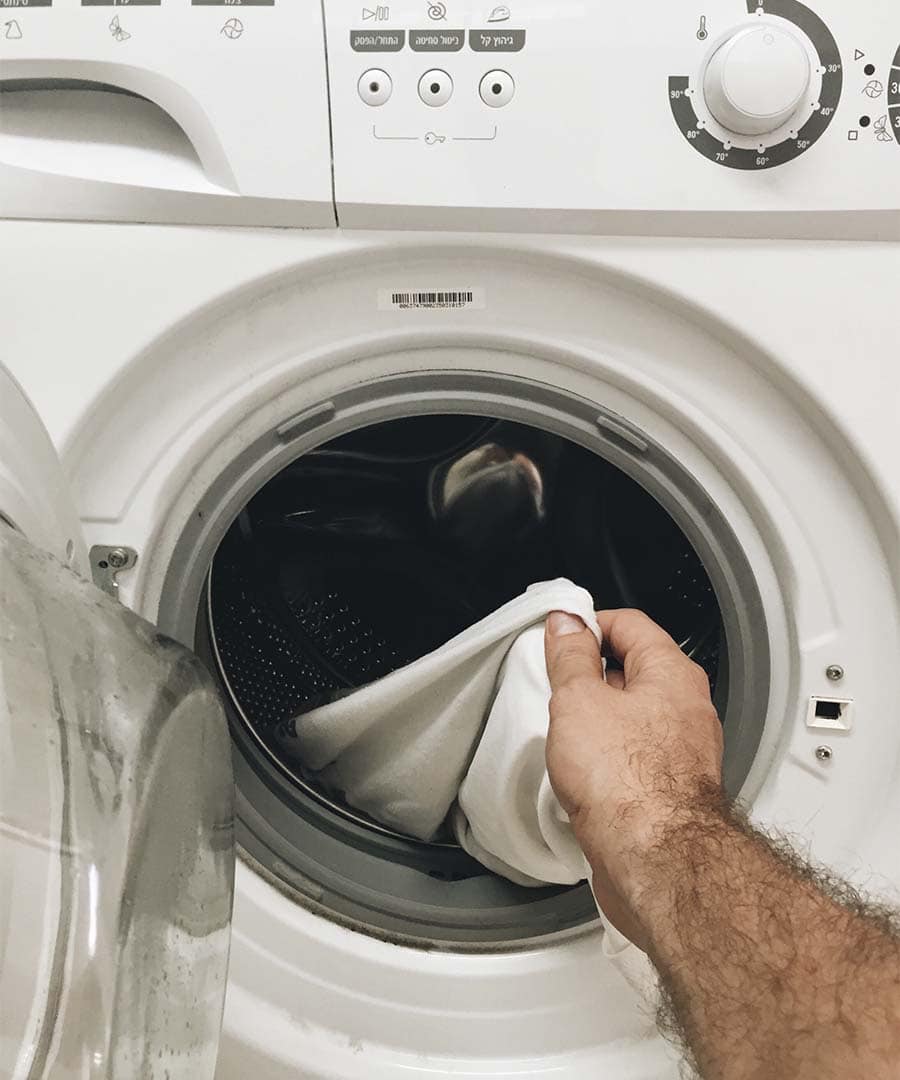 pessoa retirando roupa de máquina de lavar 